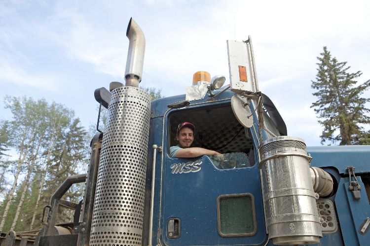 truck driver leaning against the open window of his truck